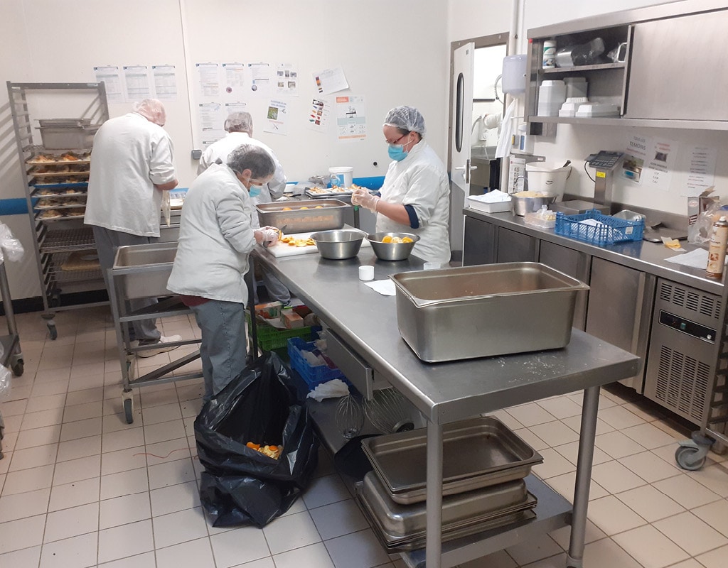 personnel d'ESAT en train de peler des oranges dans une cuisine centrale d'ESAT