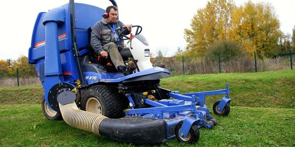 Employé sur une grosse tondeuse à gazon à 4 roues bleue